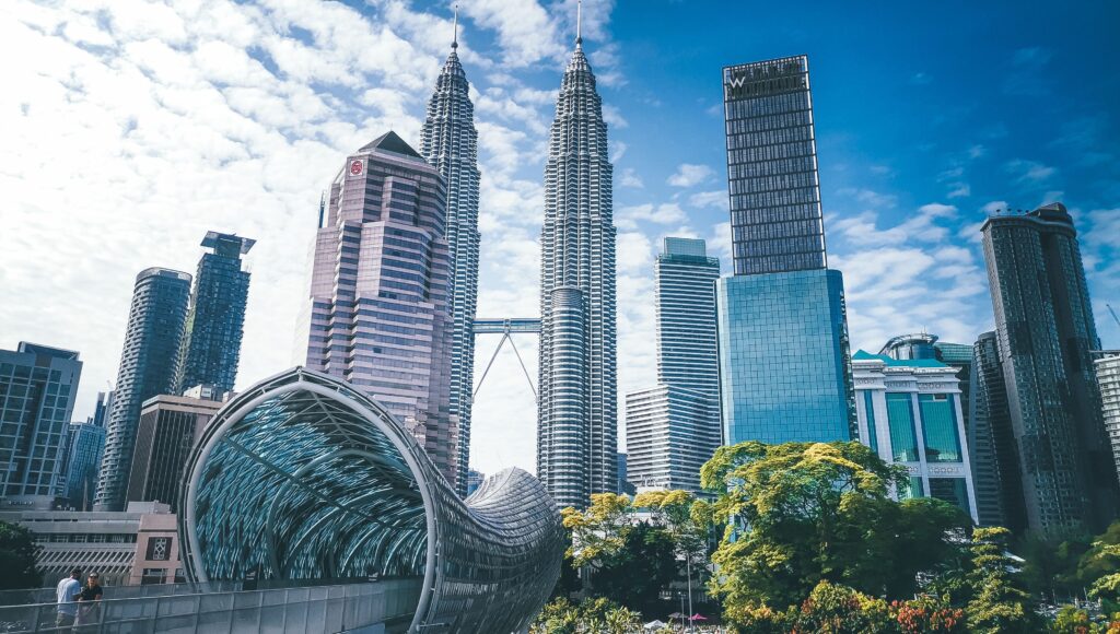 Cityscape with famous Petronas Twin Towers amidst glass contemporary skyscrapers and futuristic pedestrian overpass located in Kuala Lumpur