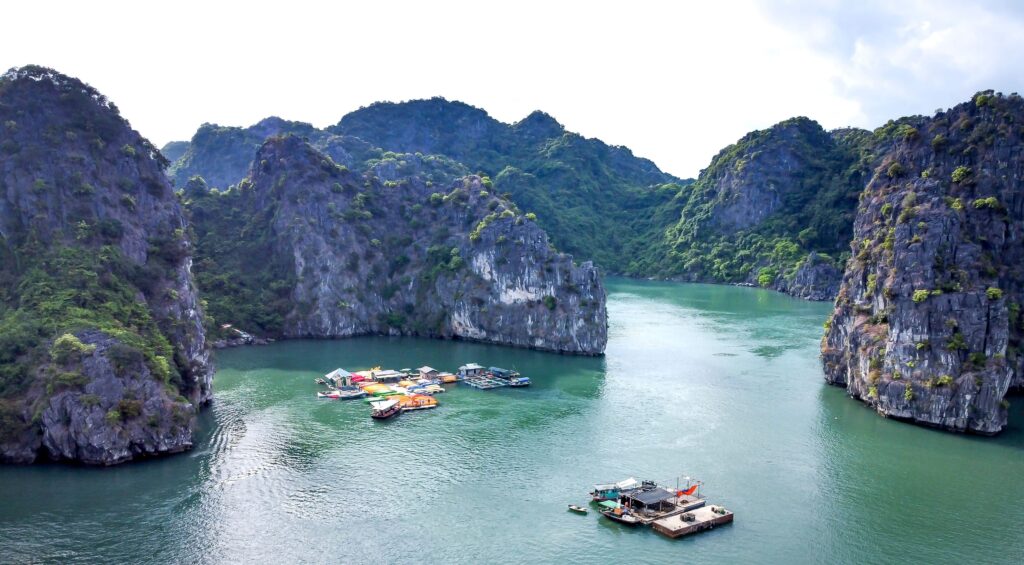 Scenic aerial view of boats in a tranquil bay surrounded by limestone cliffs.