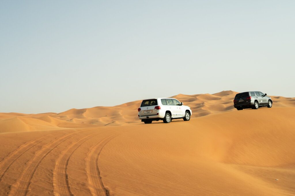 Two SUVs navigate the stunning sand dunes of Dubai, capturing adventure in the Arabian desert.