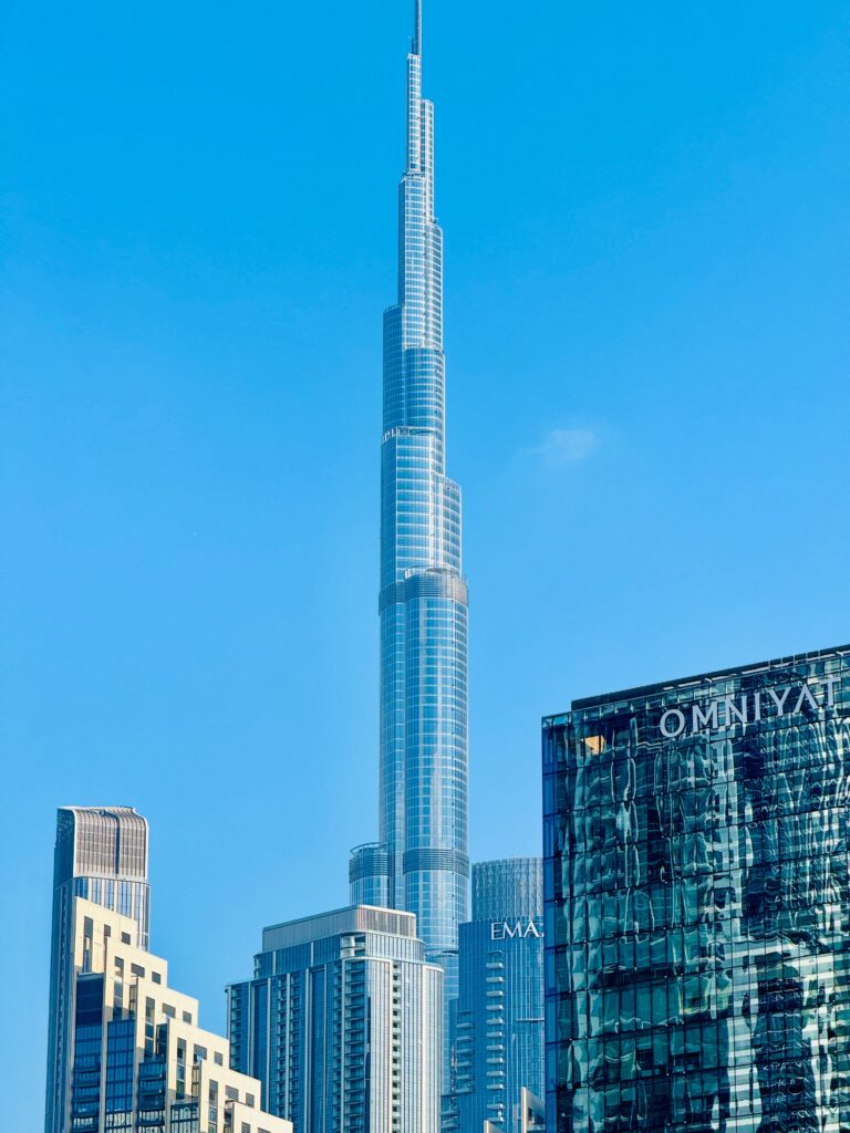Iconic Burj Khalifa surrounded by modern architecture against a clear blue sky in Dubai.