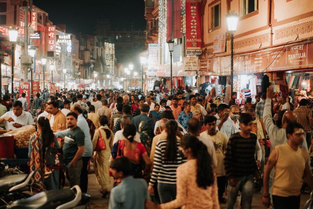 A lively and crowded night market filled with people shopping and socializing on a bustling city street.