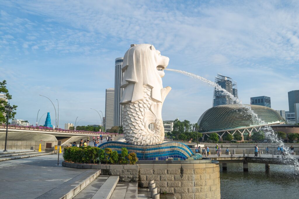 Iconic Merlion statue with Singapore skyline backdrop and Esplanade theaters.