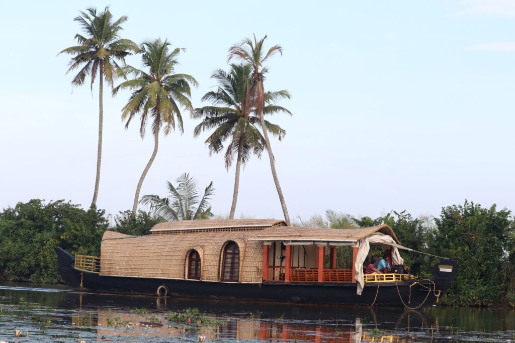 Traditional houseboat cruising on serene Kerala backwaters lined with palm trees.
